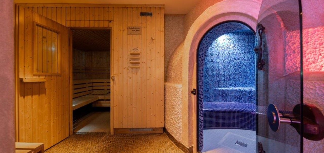 Sauna mit Holzwänden und ein angrenzendes Dampfbad mit blauen Mosaikfliesen., © Kronen Hotel GmbH