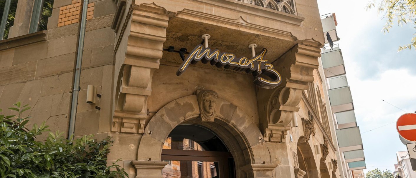 Eingang eines historischen Geb&auml;udes mit dem Schriftzug 'Mozart3' &uuml;ber dem Torbogen. Verzierungen und Pflanzen sind sichtbar., &copy; SMG, Sarah Schmid