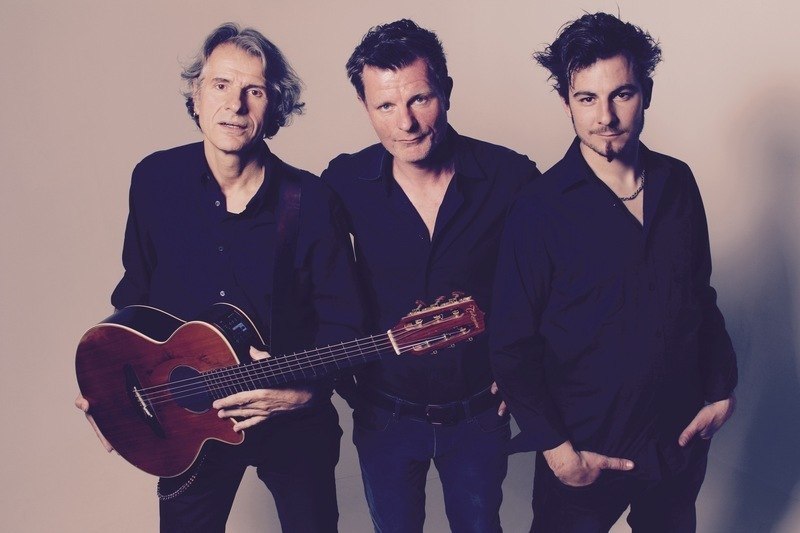 Drei Männer in schwarzer Kleidung posieren vor einem neutralen Hintergrund. Einer hält eine Gitarre., © Mauerwerk GmbH Drei Männer in schwarzer Kleidung posieren vor einem neutralen Hintergrund. Einer hält eine Gitarre., © Mauerwerk GmbH