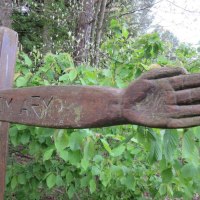 Holzskulptur eines ausgestreckten Arms mit der Inschrift 'BEIM ARM' vor gr&uuml;nem Laub im Wald., &copy; Natur.Nah. Sch&ouml;nbuch & Heckeng&auml;u