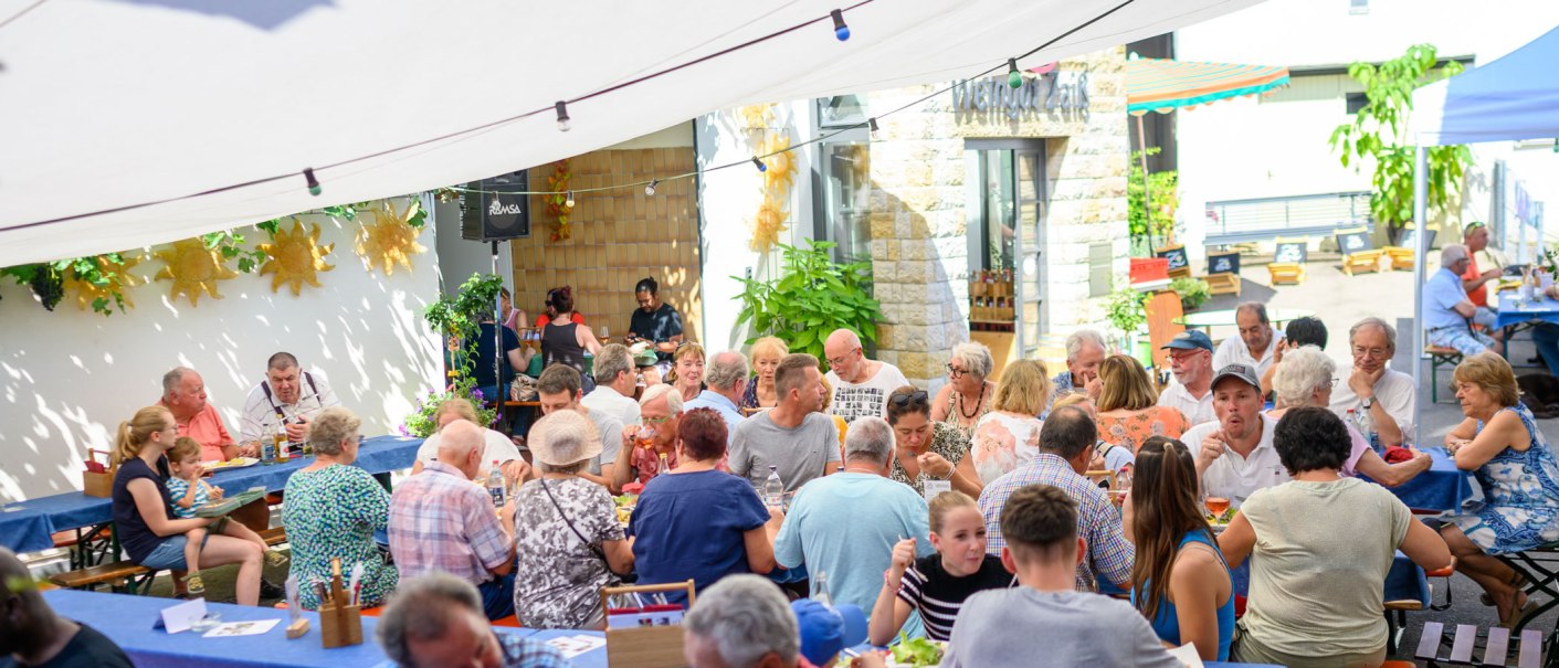 Geselliges Beisammensein im Freien bei Weingut Zaiß. Menschen genießen Essen und Getränke unter einem Sonnensegel., © Weingut Zaiß Geselliges Beisammensein im Freien bei Weingut Zaiß. Menschen genießen Essen und Getränke unter einem Sonnensegel., © Weingut Zaiß