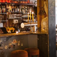Eine gem&uuml;tliche Bar mit Skateboard-Dekor auf der Theke, Kerzenleuchter und Barhockern. Im Hintergrund sind Flaschen und Gl&auml;ser zu sehen., &copy; Mata Hari, Stuttgart