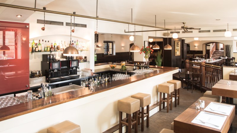 Stilvolles Restaurant mit Bar, Holzm&ouml;beln und gedeckten Tischen. Helle Beleuchtung und gem&uuml;tliche Atmosph&auml;re., &copy; Amadeus, Stuttgart