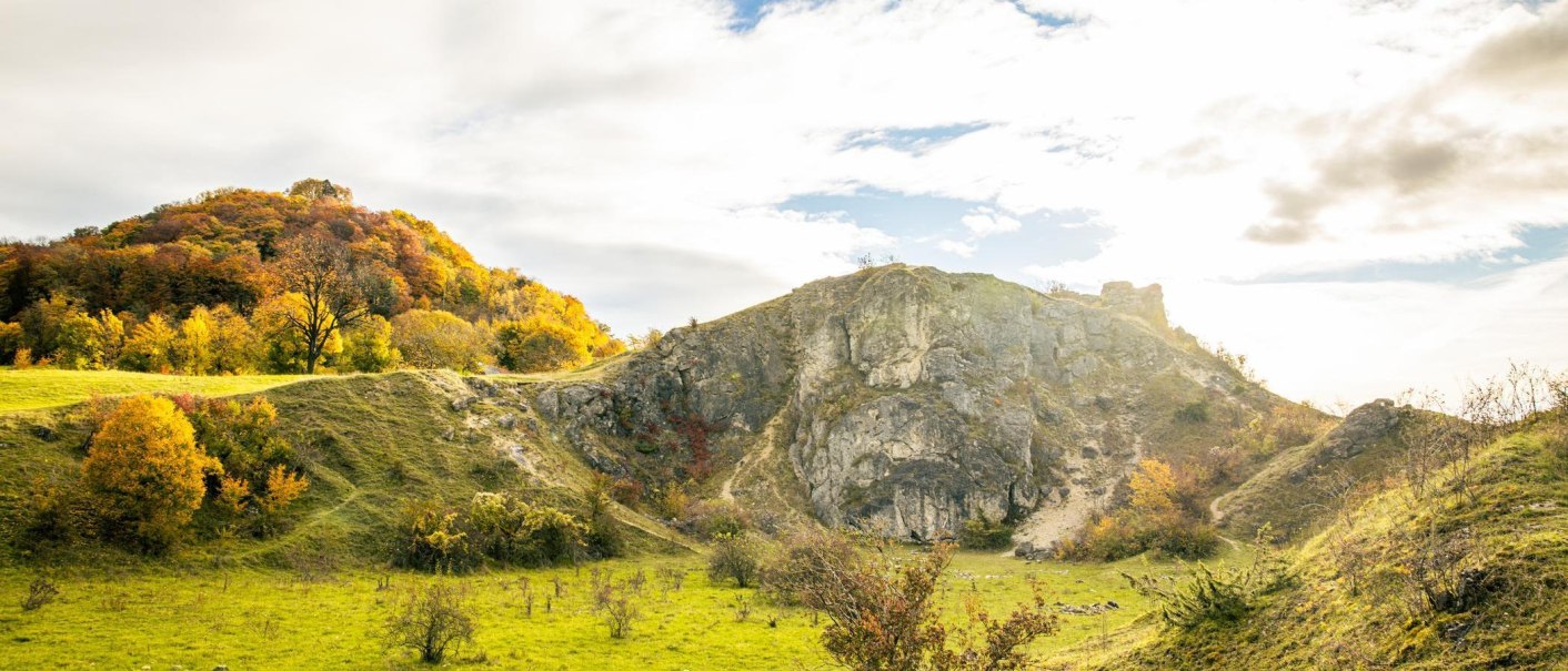 Herbstliche Landschaft mit bunten Bäumen und Felsen unter einem bewölkten Himmel. Die Sonne scheint durch die Wolken und beleuchtet die Szenerie., © Stuttgart-Marketing GmbH, Sarah Schmid Herbstliche Landschaft mit bunten Bäumen und Felsen unter einem bewölkten Himmel. Die Sonne scheint durch die Wolken und beleuchtet die Szenerie., © Stuttgart-Marketing GmbH, Sarah Schmid