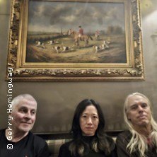 Drei Personen sitzen auf einem Sofa vor einem Gem&auml;lde mit einer Jagdszene. Die Atmosph&auml;re wirkt gem&uuml;tlich und k&uuml;nstlerisch., &copy; links im Bild