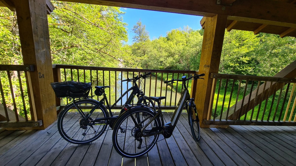 Zwei Fahrr&auml;der auf einer Holzbr&uuml;cke &uuml;ber einem Fluss, umgeben von &uuml;ppigem Gr&uuml;n und strahlend blauem Himmel., &copy; N&ouml;rdlicher Schwarzwald