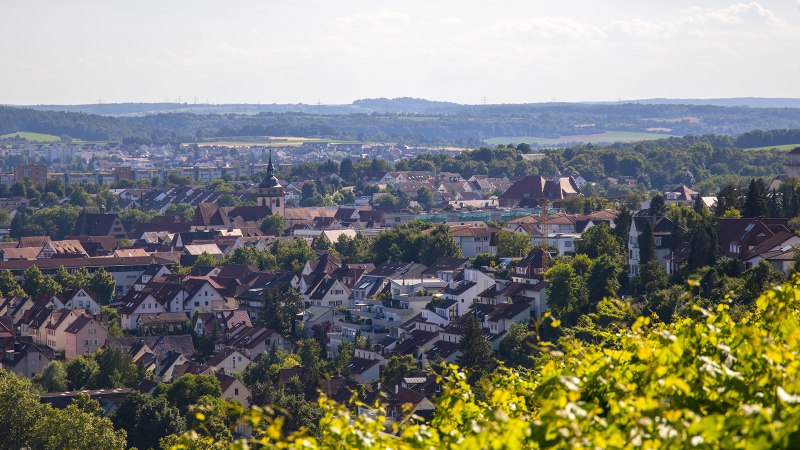 Blick von der Aussichtsplattform Lug auf eine Stadt mit vielen Häusern, umgeben von grüner Landschaft und Hügeln im Hintergrund., © SMG, Achim Mende