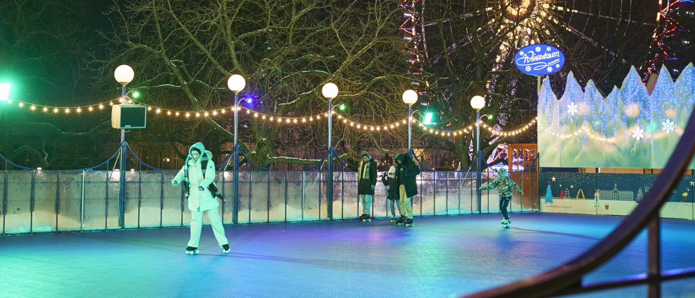 Menschen laufen auf einer beleuchteten Eisbahn im Freien. Lichterketten und ein Schild mit "Wintertraum" schaffen eine festliche Atmosphäre., © SMG, Sarah Schmid