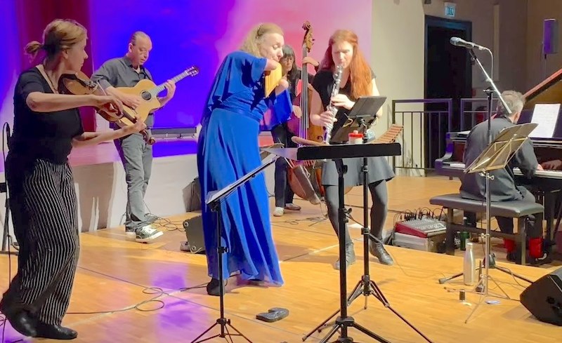Eine Gruppe von Musikern spielt auf einer Bühne. Sie nutzen Instrumente wie Gitarre, Panflöte und Klarinette. Die Atmosphäre ist lebendig und dynamisch., © Konzertbüro Hannah Schlubeck