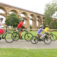 Eine Familie fährt mit Fahrrädern auf einem Weg vor dem Bietigheimer Viadukt. Im Hintergrund sind Bäume und das Viadukt zu sehen., © Land der 1000 Hügel - Kraichgau-Stromberg Eine Familie fährt mit Fahrrädern auf einem Weg vor dem Bietigheimer Viadukt. Im Hintergrund sind Bäume und das Viadukt zu sehen., © Land der 1000 Hügel - Kraichgau-Stromberg