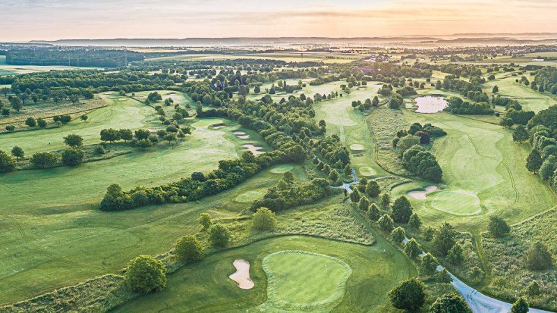Luftaufnahme des Golfclubs Domäne Niederreutin mit gepflegten Fairways, Bunkern und Clubhaus im Hintergrund bei Sonnenuntergang., © Golfclub Domäne Niederreutin