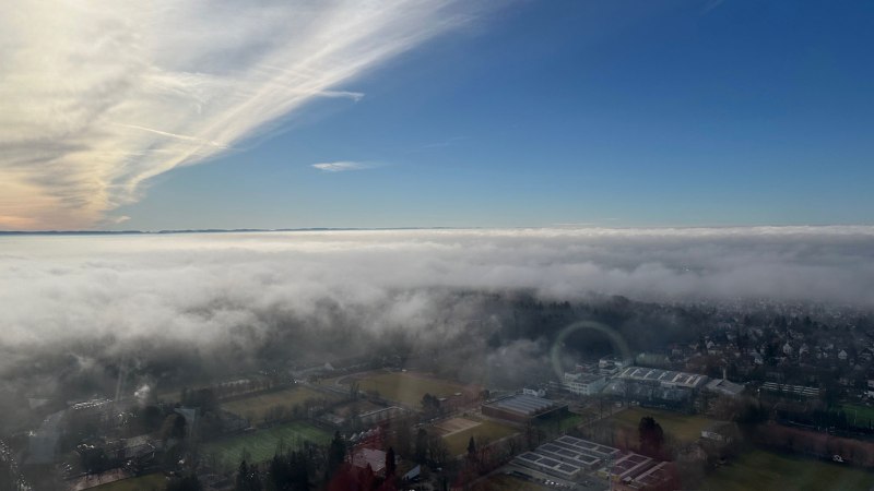 Blick vom Fernsehturm auf eine Stadt, die unter einer dichten Wolkendecke liegt. Der Himmel darüber ist klar und blau., © SMG