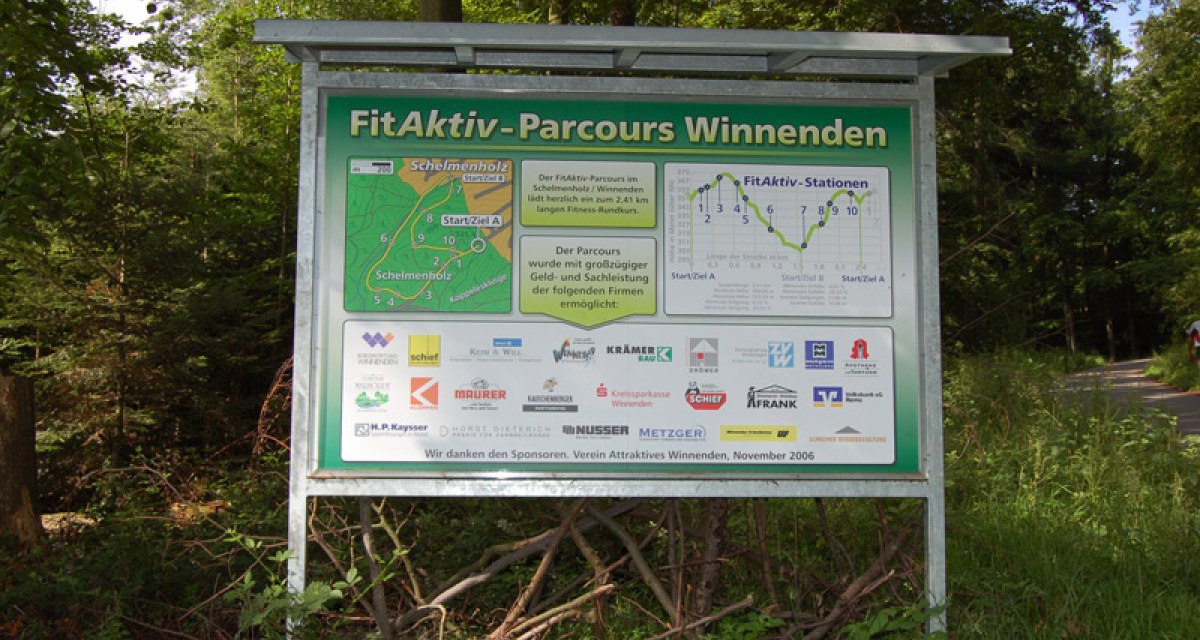 Schild des FitAktiv-Parcours Winnenden im Wald. Es zeigt eine Karte des Parcours und Logos von Sponsoren. Der Weg führt durch bewaldetes Gebiet., © Winnenden - Stuttgart-Marketing GmbH Schild des FitAktiv-Parcours Winnenden im Wald. Es zeigt eine Karte des Parcours und Logos von Sponsoren. Der Weg führt durch bewaldetes Gebiet., © Winnenden - Stuttgart-Marketing GmbH