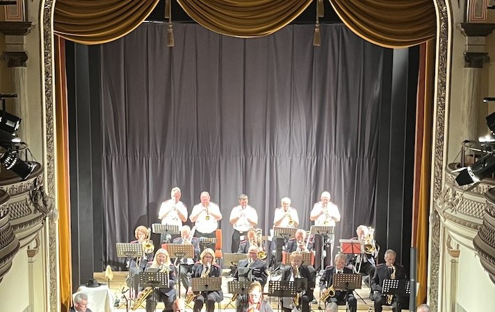 Die Brandhei&szlig; Bigband spielt auf einer eleganten Theaterb&uuml;hne. Die Musiker sind in formeller Kleidung und die B&uuml;hne ist mit goldenen Vorh&auml;ngen geschm&uuml;ckt., &copy; Touristik Bad Wildbad GmbH