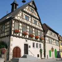 Fachwerk-Rathaus in Oberriexingen mit Blumen an den Fenstern, daneben weitere bunte Gebäude. Blauer Himmel im Hintergrund., © Land der 1000 Hügel - Kraichgau-Stromberg