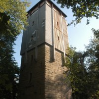 Ein hoher Turm aus Stein und Holz steht im Wald, umgeben von Bäumen. Der Himmel ist klar und sonnig., © TGMB Marbach Ein hoher Turm aus Stein und Holz steht im Wald, umgeben von Bäumen. Der Himmel ist klar und sonnig., © TGMB Marbach
