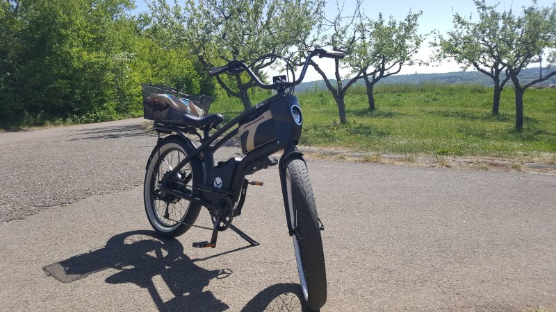 Ein schwarzes Youmo-E-Bike steht auf einer Straße in einer grünen, ländlichen Umgebung mit Bäumen im Hintergrund., © Hotel Weinstadt