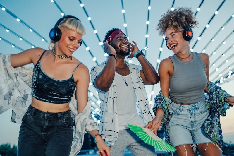 Drei Personen tanzen fr&ouml;hlich mit Kopfh&ouml;rern bei einer Silent Disco unter leuchtenden Lichterketten., &copy; EMT Event-Media-Tec GmbH