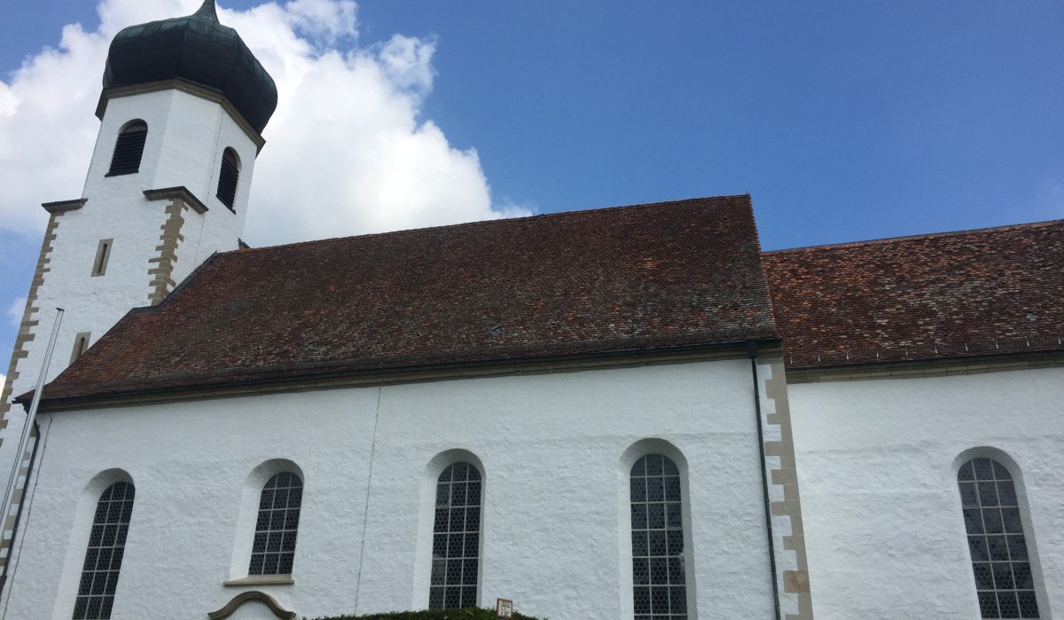 Weiße Kirche mit Zwiebelturm und roten Dachziegeln, umgeben von Hecken, vor blauem Himmel mit Wolken., © www.pro-cycl.de Weiße Kirche mit Zwiebelturm und roten Dachziegeln, umgeben von Hecken, vor blauem Himmel mit Wolken., © www.pro-cycl.de