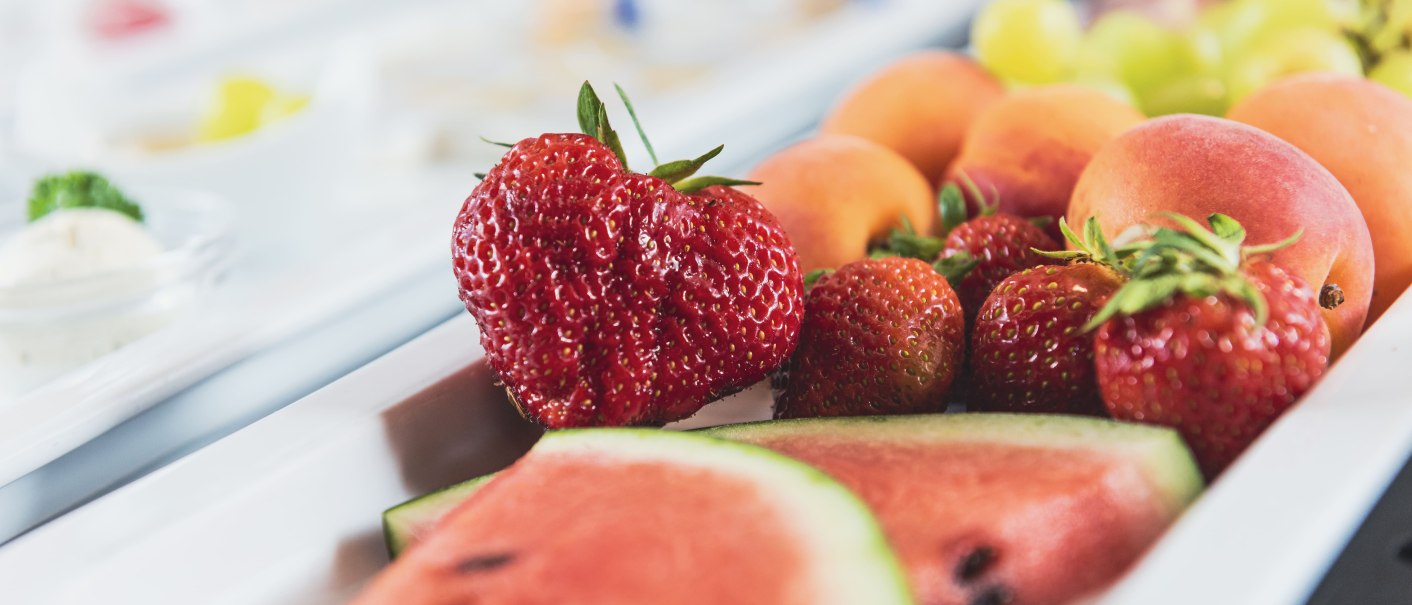 Frisches Obst auf einem Frühstücksbüffet: Erdbeeren, Melonen und Aprikosen auf einem weißen Tablett arrangiert., © VCH Hotel Wartburg