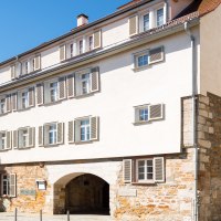 Historisches Gebäude mit Steinmauer und weißen Fensterläden, umgeben von Bäumen, unter blauem Himmel in Göppingen., © Stadtmarketing Göppingen