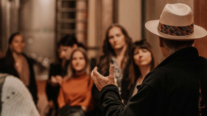 Ein Mann mit Hut spricht zu einer Gruppe von Menschen in einem Keller. Die Zuhörer wirken interessiert., © Fellbacher Weingärtner eG Ein Mann mit Hut spricht zu einer Gruppe von Menschen in einem Keller. Die Zuhörer wirken interessiert., © Fellbacher Weingärtner eG