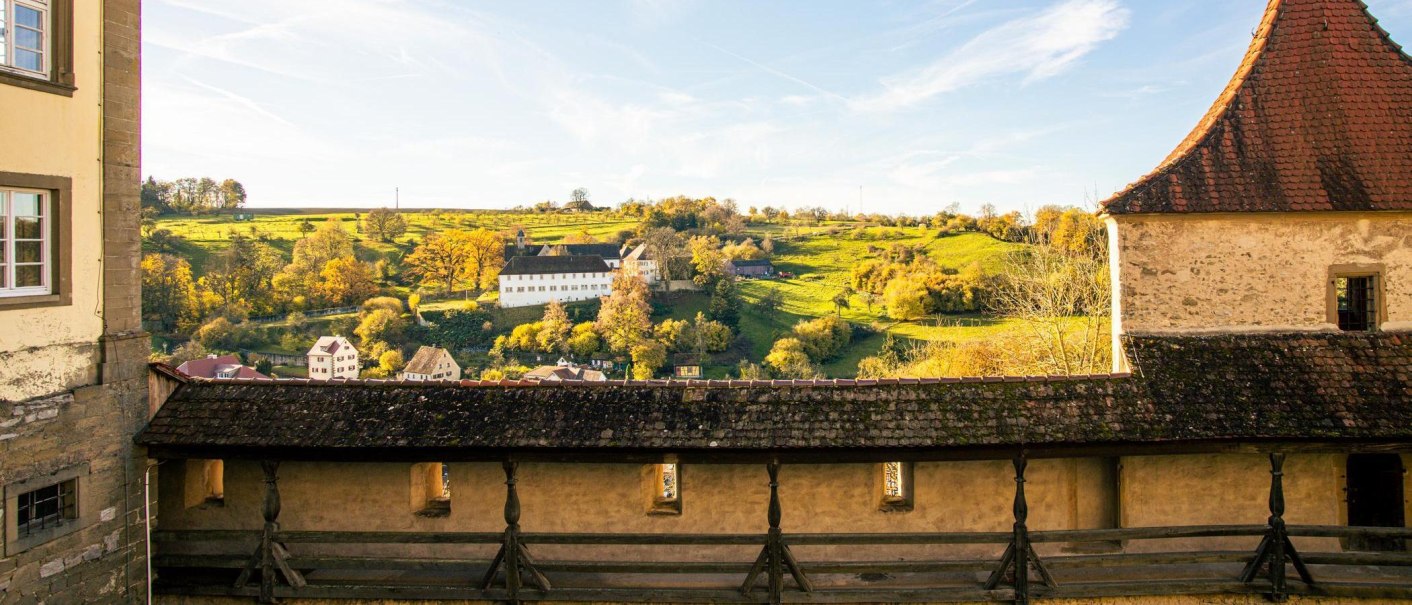 Blick von der Großcomburg auf eine malerische Landschaft mit einem weißen Gebäude und herbstlichen Bäumen im Hintergrund., © Stuttgart-Marketing GmbH, Sarah Schmid