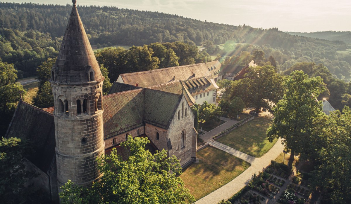 Luftaufnahme des Klosters Lorch, umgeben von grünen Bäumen und Hügeln. Die Sonne scheint auf die historischen Gebäude und den gepflegten Garten., © Tourismus Ostalb