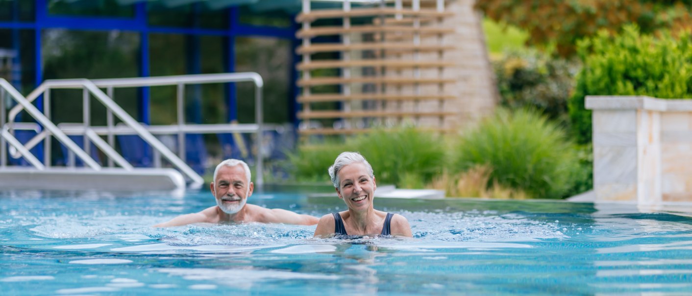 Ein &auml;lteres Paar genie&szlig;t das Schwimmen in einem Au&szlig;enpool einer Therme. Sie wirken entspannt und gl&uuml;cklich., &copy; Thomas Niederm&uuml;ller