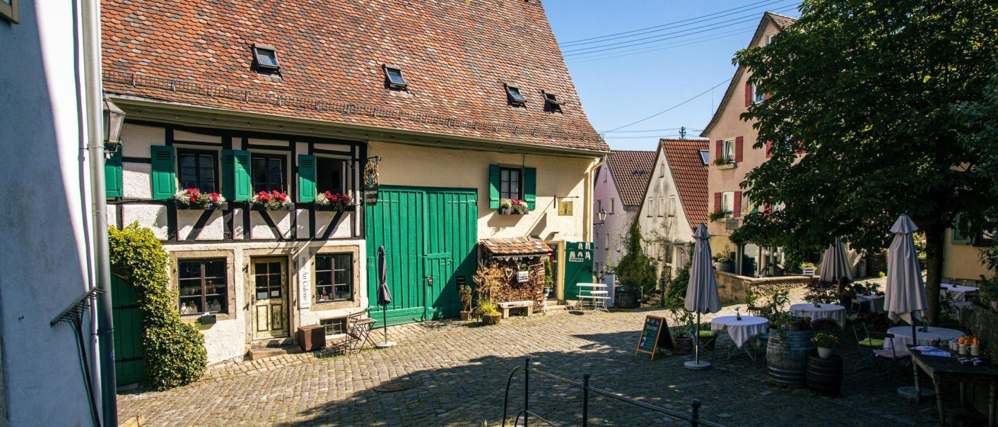 Ein idyllischer Innenhof in Nürtingens Altstadt mit Fachwerkhaus, grünen Fensterläden und gemütlichen Sitzgelegenheiten unter einem Baum., © Stuttgart-Marketing GmbH, Sarah Schmid