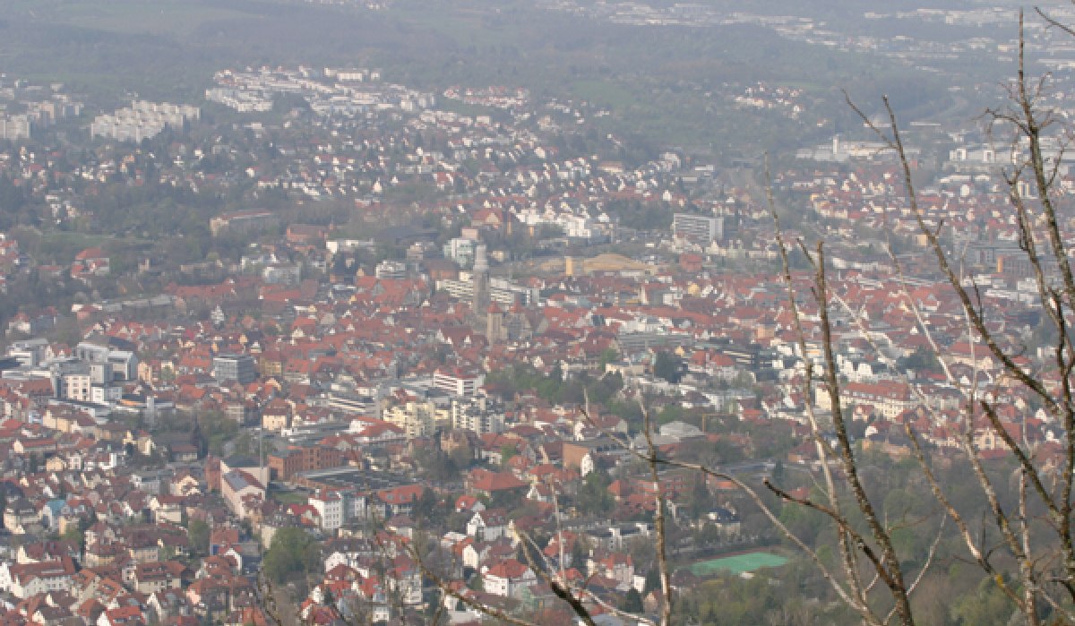 Panoramablick auf eine Stadt mit roten Dächern, umgeben von grünen Hügeln und Bäumen im Vordergrund., © Mythos Schwäbische Alb im Landkreis Reutlingen e.V. Panoramablick auf eine Stadt mit roten Dächern, umgeben von grünen Hügeln und Bäumen im Vordergrund., © Mythos Schwäbische Alb im Landkreis Reutlingen e.V.