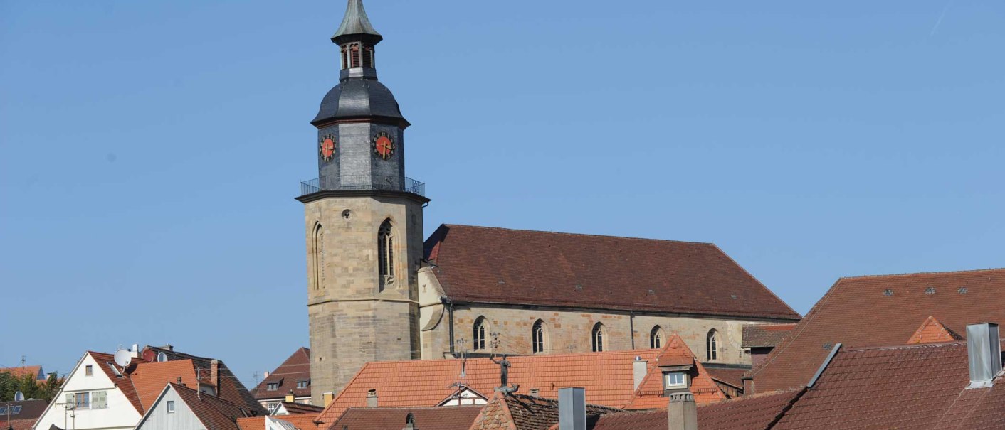 Die Evangelische Stadtkirche mit ihrem markanten Turm erhebt sich &uuml;ber die D&auml;cher der umliegenden H&auml;user unter einem klaren blauen Himmel., &copy; Stadt Vaihingen an der Enz