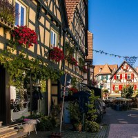 Malerische Altstadtstra&szlig;e in Besigheim mit Fachwerkh&auml;usern, bl&uuml;henden Blumen und einem blauen Verkaufswagen unter klarem Himmel., &copy; Stuttgart-Marketing GmbH, Sarah Schmid