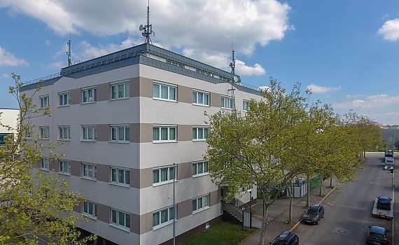 Mehrstöckiges Gebäude mit Antennen auf dem Dach, umgeben von Bäumen und parkenden Autos. Der Himmel ist leicht bewölkt., © Centro Hotels Mehrstöckiges Gebäude mit Antennen auf dem Dach, umgeben von Bäumen und parkenden Autos. Der Himmel ist leicht bewölkt., © Centro Hotels