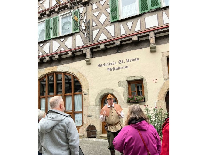 Ein Mann in historischer Kleidung erklärt einer Gruppe von Menschen etwas vor einem Fachwerkhaus mit der Aufschrift 'Weinstube St. Urban Restaurant'., © Eigenbetrieb Tourismus und Citymanagement Schorndorf Ein Mann in historischer Kleidung erklärt einer Gruppe von Menschen etwas vor einem Fachwerkhaus mit der Aufschrift 'Weinstube St. Urban Restaurant'., © Eigenbetrieb Tourismus und Citymanagement Schorndorf