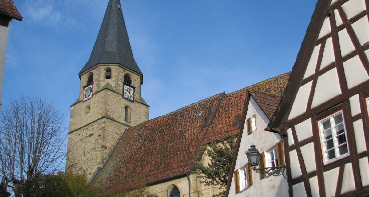 Die Sankt Martinskirche mit ihrem markanten Turm steht neben Fachwerkh&auml;usern unter einem klaren blauen Himmel., &copy; Land der 1000 H&uuml;gel - Kraichgau-Stromberg