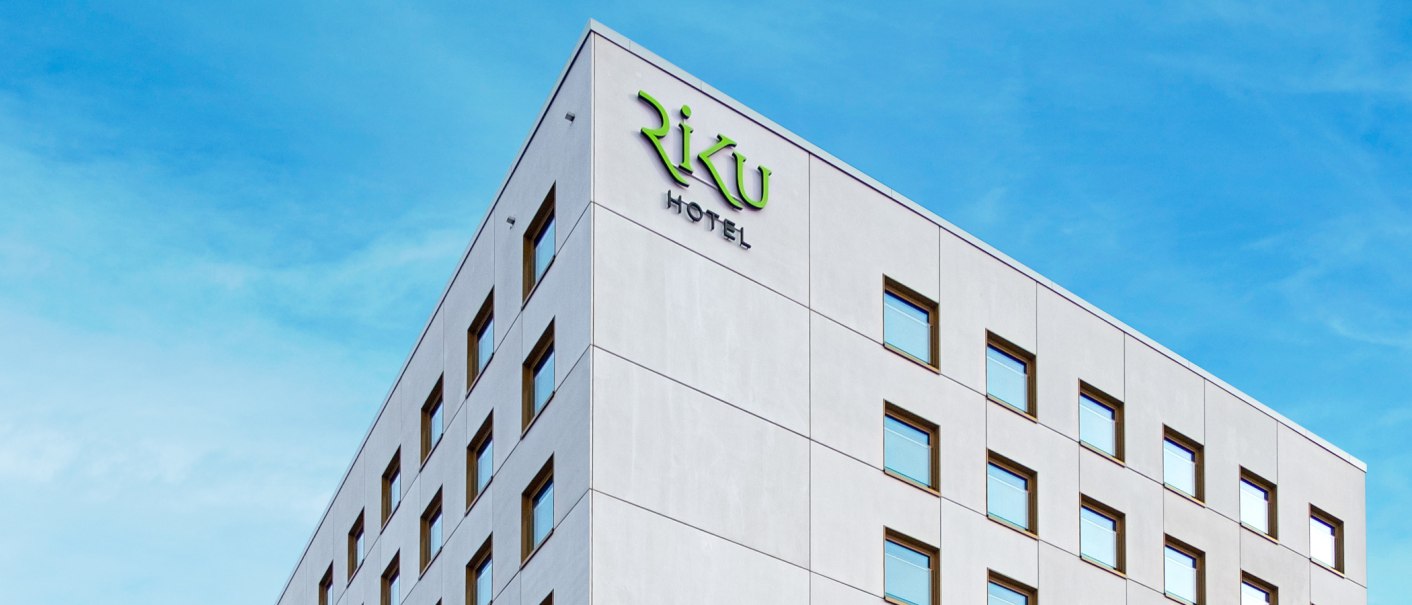 Modernes Hotelgebäude mit 'RiKu Hotel' Schriftzug vor blauem Himmel., © 13 6 Design GmbH (Judenhof 10, 89073 Ulm)