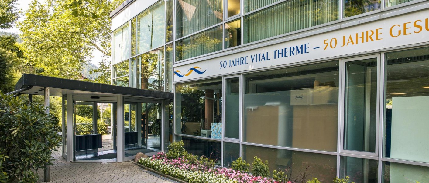 Eingang der Vital Therme mit moderner Glasfassade, umgeben von grünen Bäumen und einem gepflegten Blumenbeet. Ein Schild feiert 50 Jahre Vital Therme., © Stuttgart-Marketing GmbH, Sarah Schmid Eingang der Vital Therme mit moderner Glasfassade, umgeben von grünen Bäumen und einem gepflegten Blumenbeet. Ein Schild feiert 50 Jahre Vital Therme., © Stuttgart-Marketing GmbH, Sarah Schmid