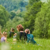Menschen sitzen auf einer blühenden Wiese, umgeben von grünen Bäumen. Sie genießen die Natur in entspannter Atmosphäre., © Stadt Waldenbuch