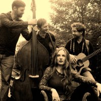 Ein Jazz-Quartett posiert im Freien. Eine Frau sitzt, w&auml;hrend drei M&auml;nner mit Kontrabass und Gitarre um sie herumstehen. Sepia-Ton., &copy; Stadt Murrhardt