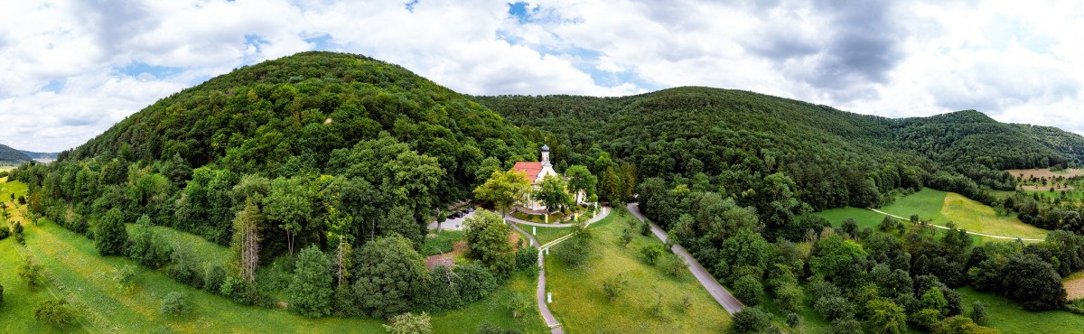 Luftaufnahme der Wallfahrtskirche Ave Maria Deggingen, eingebettet in eine grüne Waldlandschaft mit Hügeln im Hintergrund., © Landkreis Göppingen