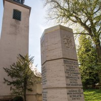 Die Evangelische Stiftskirche Bad Boll mit einem Denkmal im Vordergrund, umgeben von Bäumen und einer Laterne., © SMG, Achim Mende