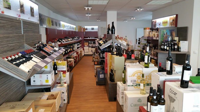 Ein Weinladen mit Regalen voller Weinflaschen und Kartons. Der Boden ist aus Holz, die Beleuchtung ist hell., © Weinhaus Gallier