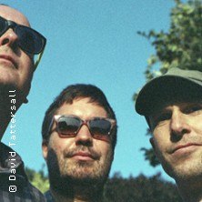 Drei Männer mit Sonnenbrillen schauen in die Ferne. Der Himmel ist blau und im Hintergrund sind Bäume zu sehen., © links im Bild Drei Männer mit Sonnenbrillen schauen in die Ferne. Der Himmel ist blau und im Hintergrund sind Bäume zu sehen., © links im Bild