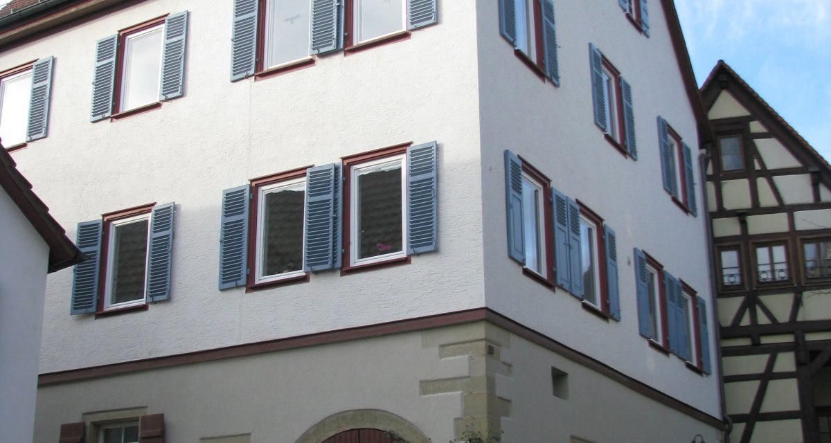Ein dreist&ouml;ckiges, wei&szlig;es Geb&auml;ude mit roten Dachziegeln und blauen Fensterl&auml;den. Es hat einen gro&szlig;en Torbogen und steht auf einem gepflasterten Platz., &copy; Land der 1000 H&uuml;gel - Kraichgau-Stromberg