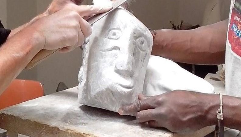 Zwei Personen bearbeiten eine Steinskulptur mit einem Gesicht. Eine Person feilt, w&auml;hrend die andere die Skulptur h&auml;lt. Der Workshop findet in Ludwigsburg statt., &copy; Kunstschule Labyrinth