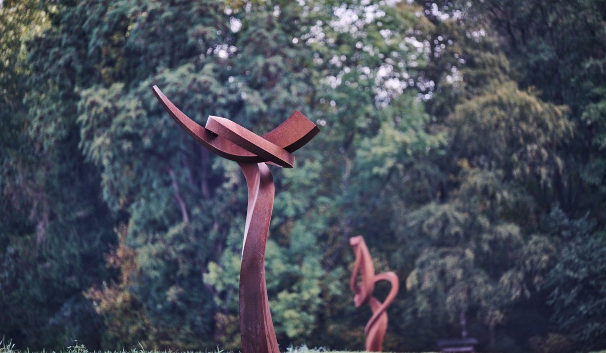 Zwei abstrakte Metallskulpturen stehen in einem Park vor einer Kulisse aus grünen Bäumen., © Natur.Nah. Schönbuch & Heckengäu Zwei abstrakte Metallskulpturen stehen in einem Park vor einer Kulisse aus grünen Bäumen., © Natur.Nah. Schönbuch & Heckengäu
